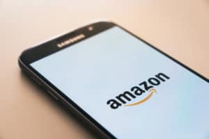 In this photo a smartphone on a table with Amazon logo on a screen.